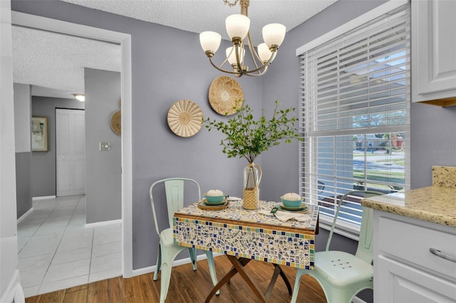 dining area with a notable chandelier, a wealth of natural light, a textured ceiling, and light tile patterned flooring