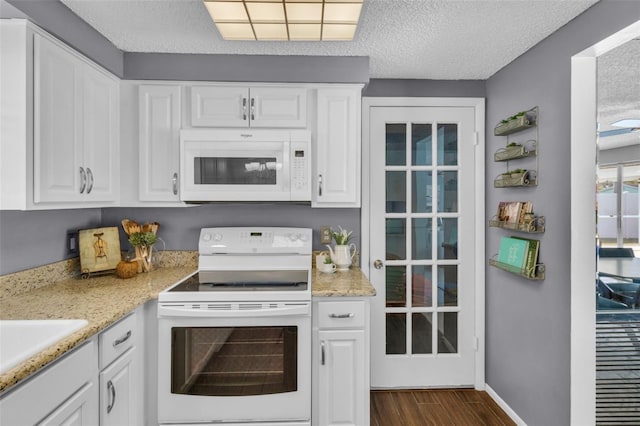 kitchen featuring white appliances, dark wood-type flooring, white cabinetry, light stone counters, and a textured ceiling