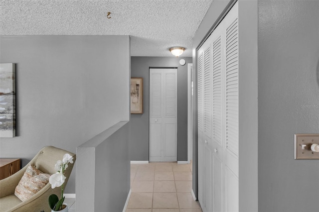 hall with a textured ceiling and light tile patterned flooring