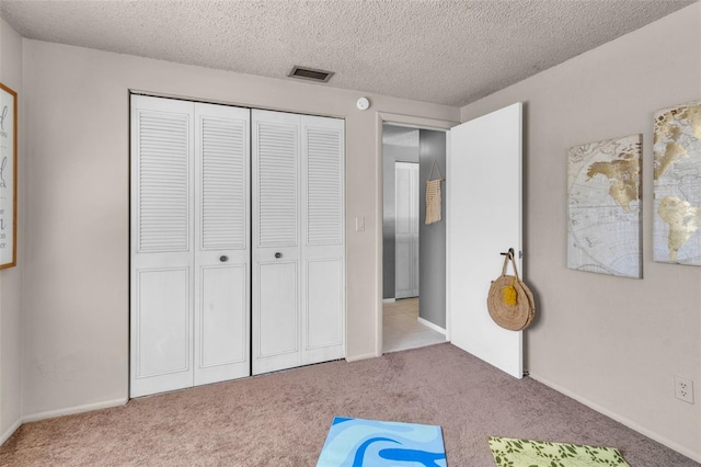 unfurnished bedroom featuring light carpet, a closet, and a textured ceiling