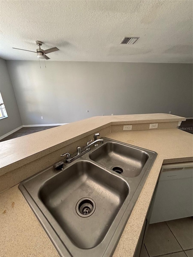 interior details with sink, ceiling fan, white dishwasher, and a textured ceiling