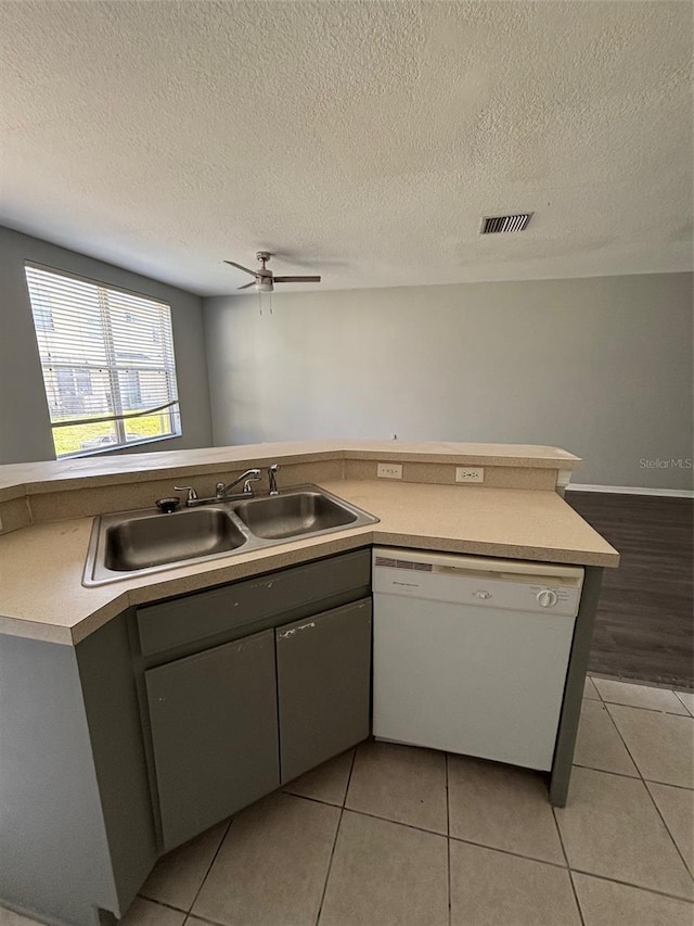 kitchen with sink, dishwasher, ceiling fan, light tile patterned floors, and kitchen peninsula