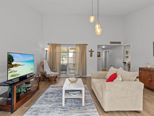 living area featuring a high ceiling, wood finished floors, and visible vents