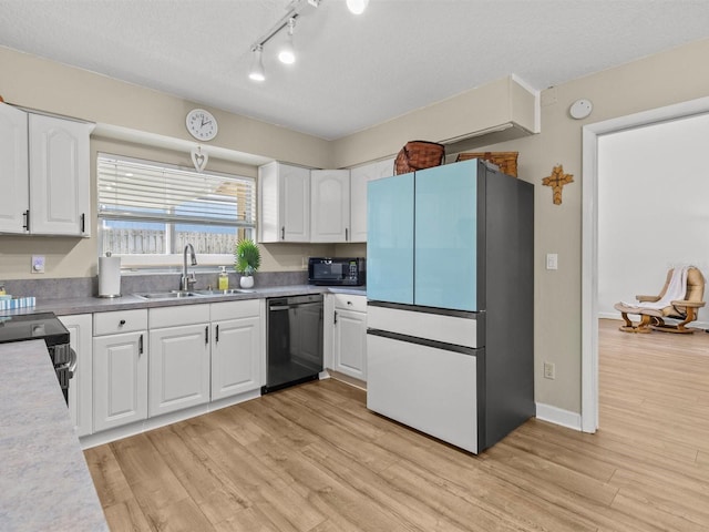 kitchen featuring white cabinets, light wood-style floors, light countertops, black appliances, and a sink