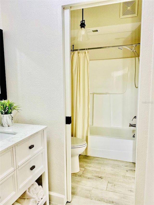 bathroom with toilet, wood finished floors, visible vents, vanity, and shower / bath combo with shower curtain