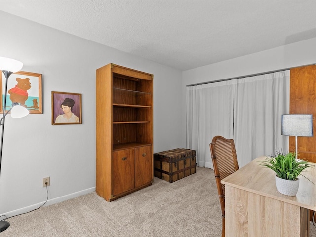carpeted office with baseboards and a textured ceiling