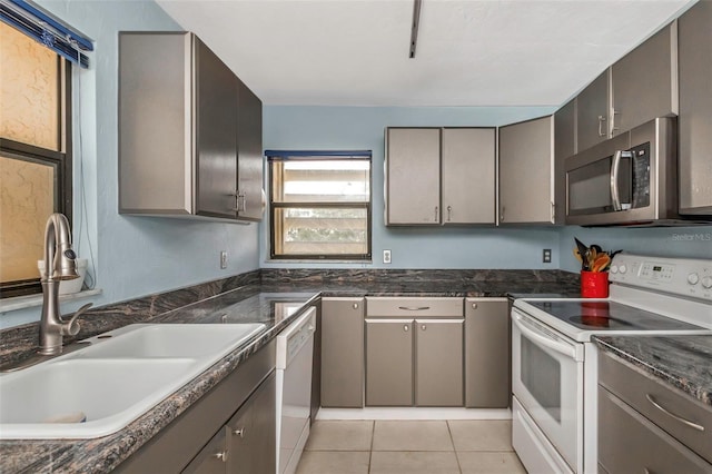 kitchen featuring white appliances, light tile patterned floors, gray cabinetry, and sink