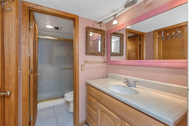 bathroom with toilet, walk in shower, tile patterned floors, vanity, and a textured ceiling