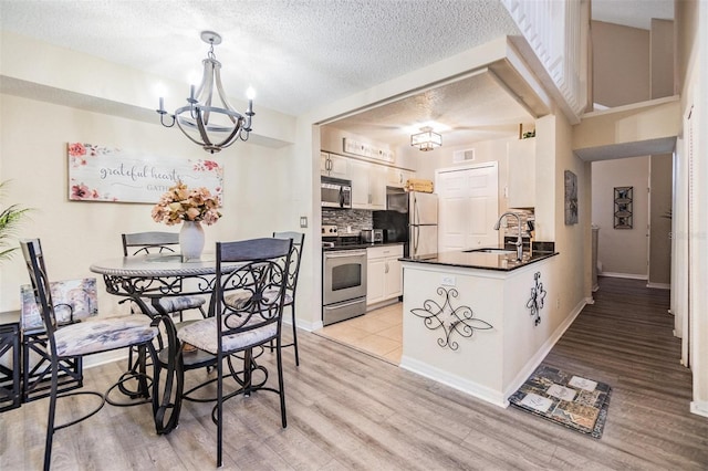 dining room featuring sink, light hardwood / wood-style floors, an inviting chandelier, and a textured ceiling