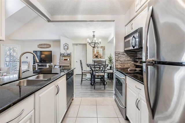 kitchen with pendant lighting, light tile patterned floors, white cabinets, appliances with stainless steel finishes, and sink