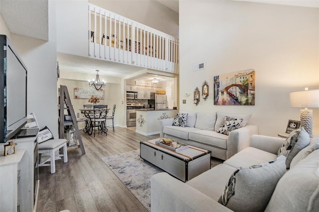 living room with a high ceiling, a chandelier, and hardwood / wood-style flooring