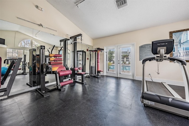 workout area with lofted ceiling, track lighting, and a textured ceiling