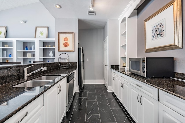 kitchen with white cabinets, stainless steel appliances, dark stone countertops, and sink