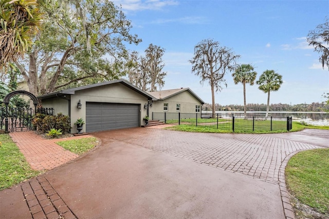 ranch-style house with a front lawn, a garage, and a water view