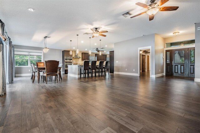 dining area with a textured ceiling, ceiling fan, and dark hardwood / wood-style flooring