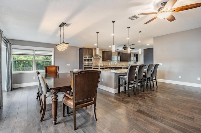 dining area with ceiling fan with notable chandelier and dark hardwood / wood-style flooring