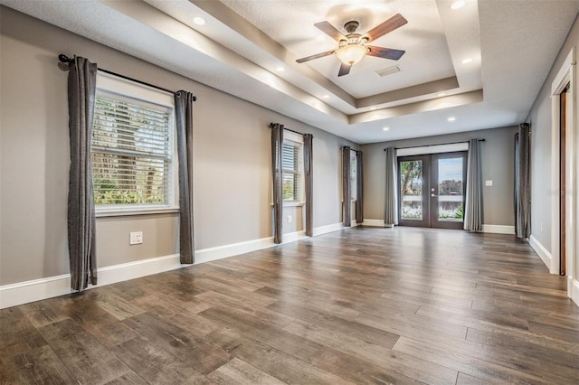 empty room featuring ceiling fan, french doors, hardwood / wood-style flooring, and a tray ceiling