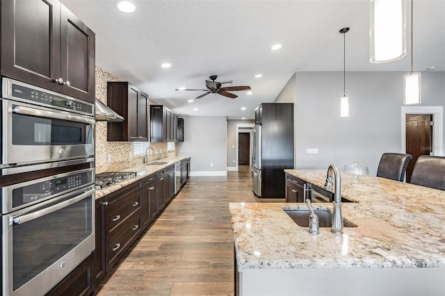 kitchen featuring hardwood / wood-style flooring, decorative light fixtures, a kitchen bar, backsplash, and sink