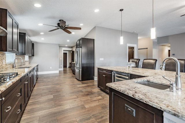 kitchen with ceiling fan, backsplash, hanging light fixtures, and sink