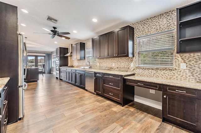 kitchen featuring appliances with stainless steel finishes, light stone countertops, ceiling fan, dark brown cabinetry, and sink