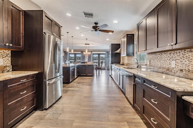 kitchen with sink, stainless steel appliances, backsplash, and hanging light fixtures