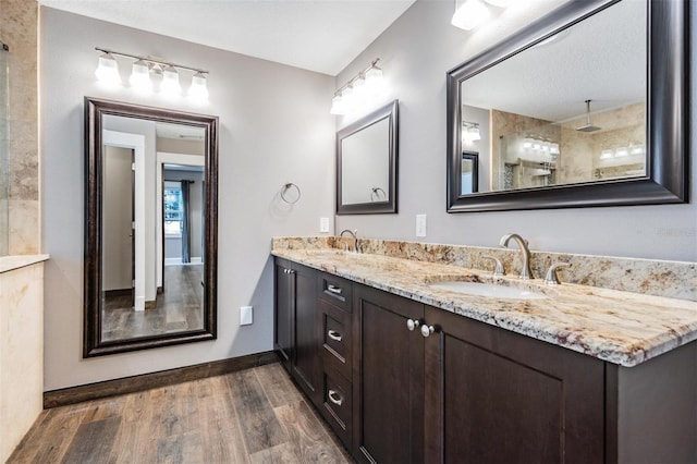 bathroom with wood-type flooring, vanity, and tiled shower