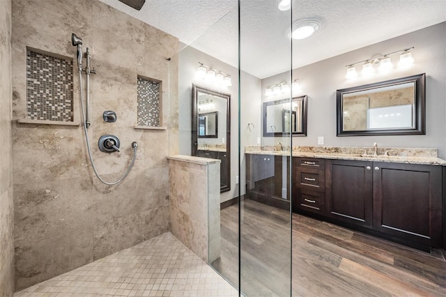 bathroom featuring a textured ceiling, tiled shower, hardwood / wood-style floors, and vanity