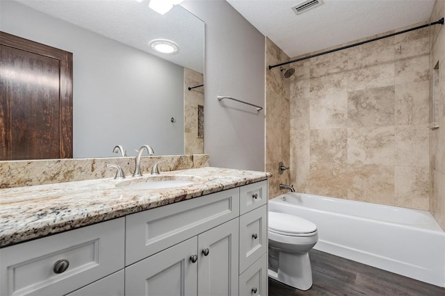 full bathroom featuring toilet, a textured ceiling, hardwood / wood-style floors, tiled shower / bath, and vanity