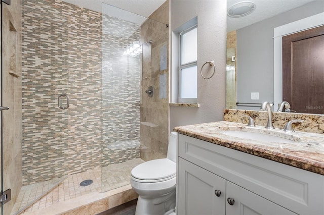 bathroom featuring toilet, a shower with door, and vanity