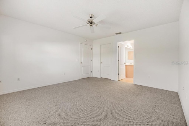 unfurnished bedroom featuring ceiling fan, light carpet, and ensuite bath