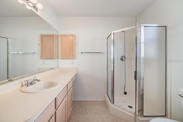 bathroom featuring toilet, a shower with shower door, and vanity