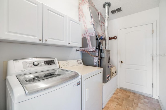 clothes washing area with separate washer and dryer and cabinets