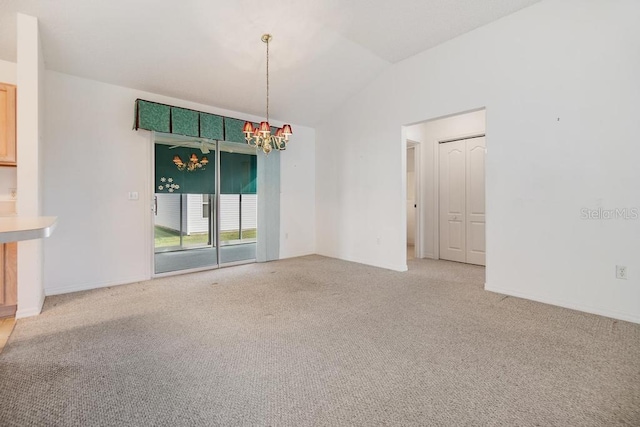 carpeted spare room featuring a chandelier and vaulted ceiling