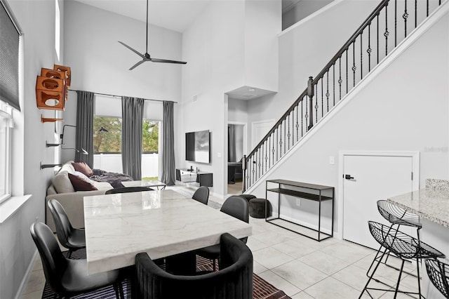 tiled dining room featuring ceiling fan and a towering ceiling