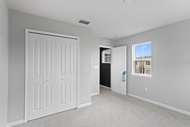 unfurnished bedroom with a closet and light colored carpet