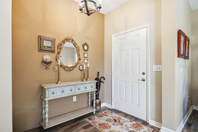 entryway with dark wood-type flooring and a chandelier