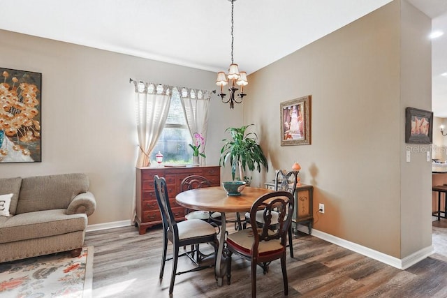 dining room with dark hardwood / wood-style floors and an inviting chandelier