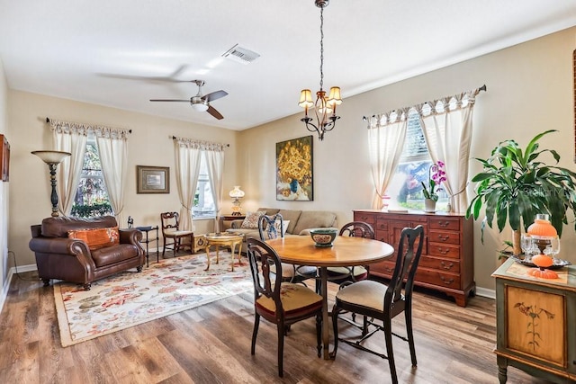 dining space featuring ceiling fan with notable chandelier and dark hardwood / wood-style floors