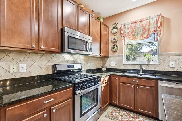 kitchen with decorative backsplash, sink, stainless steel appliances, and dark stone counters