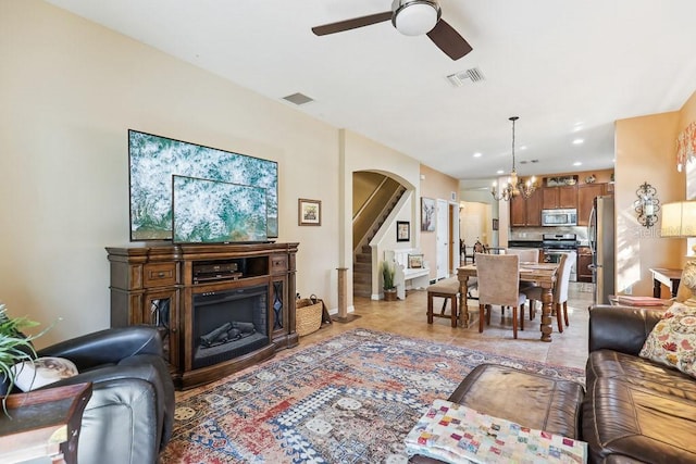 living room with light tile patterned flooring and ceiling fan with notable chandelier