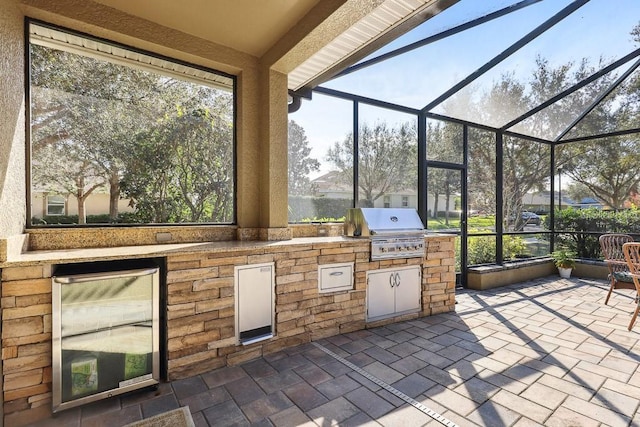 view of patio / terrace featuring glass enclosure, a grill, beverage cooler, and area for grilling