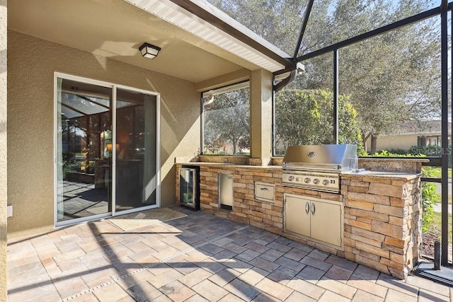 view of patio / terrace with a lanai, an outdoor kitchen, area for grilling, and wine cooler