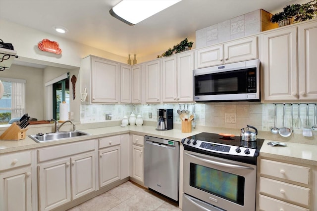 kitchen featuring backsplash, light tile patterned flooring, sink, white cabinetry, and stainless steel appliances