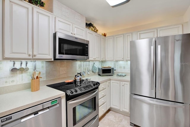 kitchen with backsplash, white cabinetry, appliances with stainless steel finishes, and light tile patterned flooring