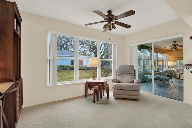 living area with a wealth of natural light, carpet, and ceiling fan