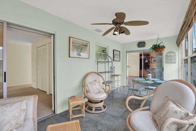 living area featuring ceiling fan and dark tile patterned flooring