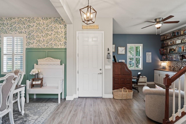 foyer entrance featuring ceiling fan with notable chandelier and hardwood / wood-style floors