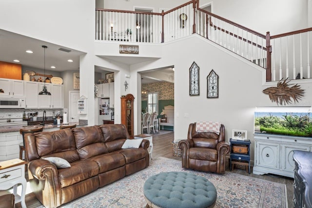 living room featuring a high ceiling, sink, and wood-type flooring