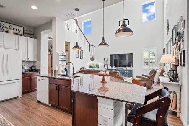 kitchen featuring white appliances, decorative light fixtures, white cabinetry, dark stone counters, and sink