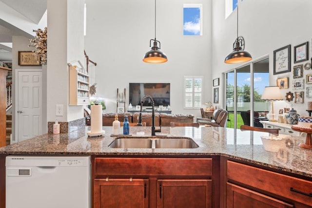 kitchen with white dishwasher, light stone countertops, pendant lighting, and sink